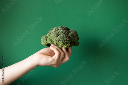 Raw broccoli in hand. Vegetarian food or diet concept.