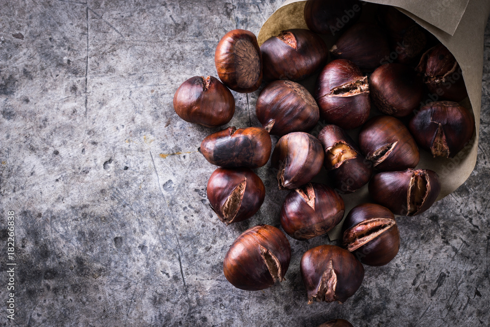 Obraz premium Roasted chestnuts on an old board. healthy food concept