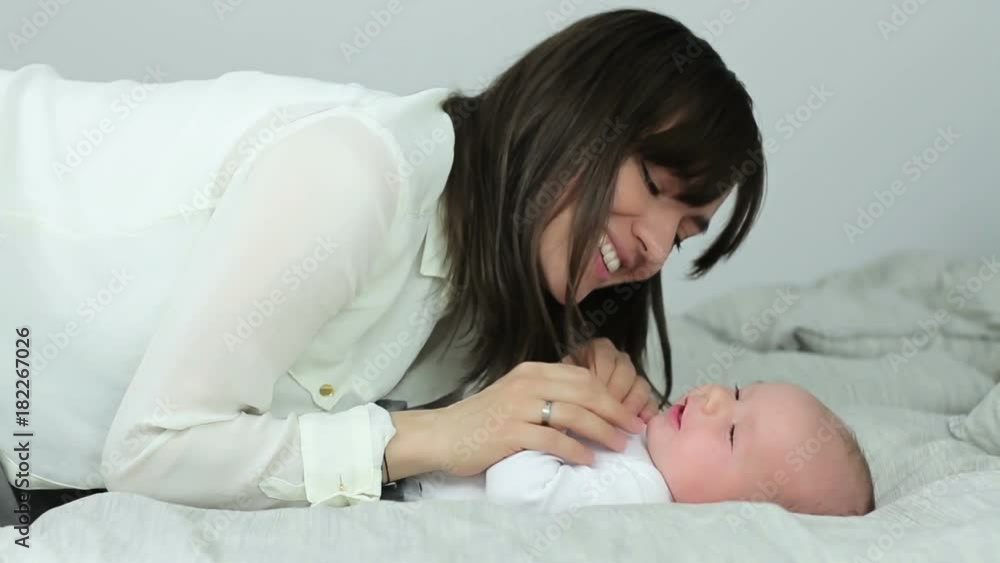Happy mother with baby lying on bed Happy mother with baby lying on bed