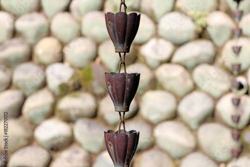 Japanese drainage chain from rain gutter and stone wall background, to prevent slipping from flood water and protect for droplet to head.