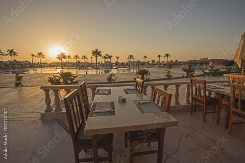 Outdoor dining table with sunset in tropical hotel resort