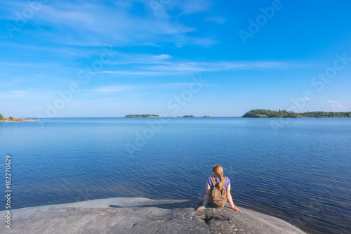 Landscape on a big lake and a girl sitting on a stone shore