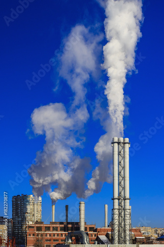 White smoke goes from a pipe on a background of blue cloudless sky