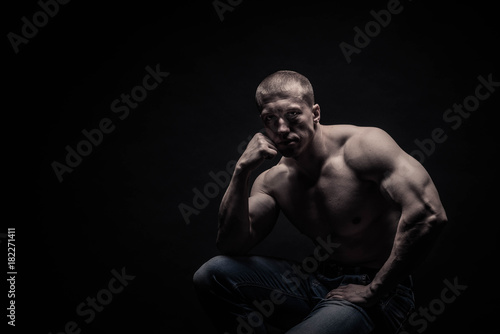 portrait of a seated male bodybuilder, on a black background isolated. monochrome. The concept of a photo of competing sports, health, fitness