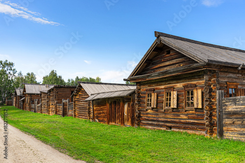 A wooden huts on the street of the Siberian village at summer. Architectural ethnographic Museum Taltsy on the shore of the Angara river near lake Baikal