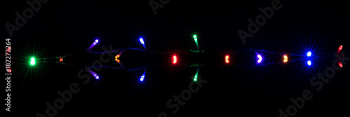 Fototapeta Naklejka Na Ścianę i Meble -  Christmas lights on reflective black background. Holiday shiny garland border. Xmas ligts concept