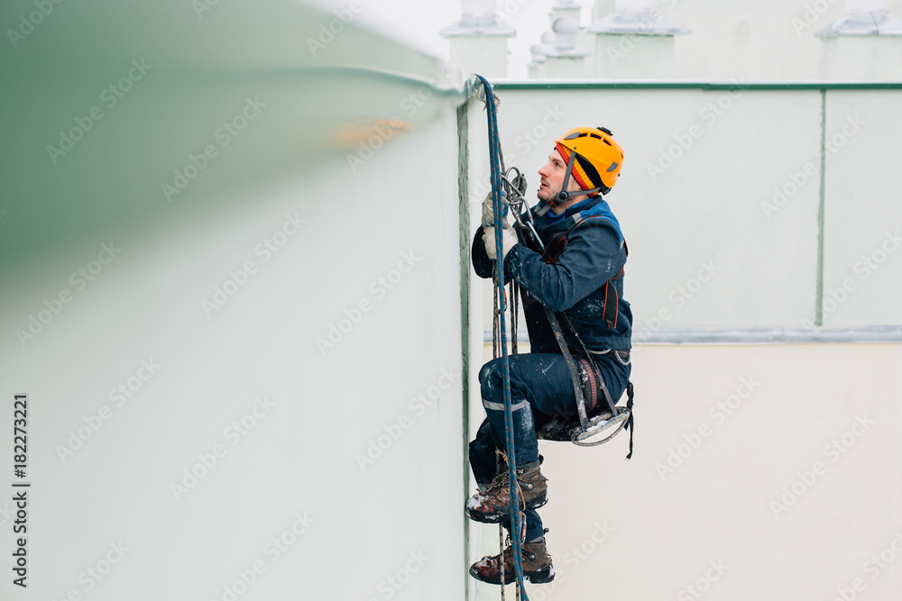 Professional industrial climber in helmet and uniform works at height. Risky extreme job.