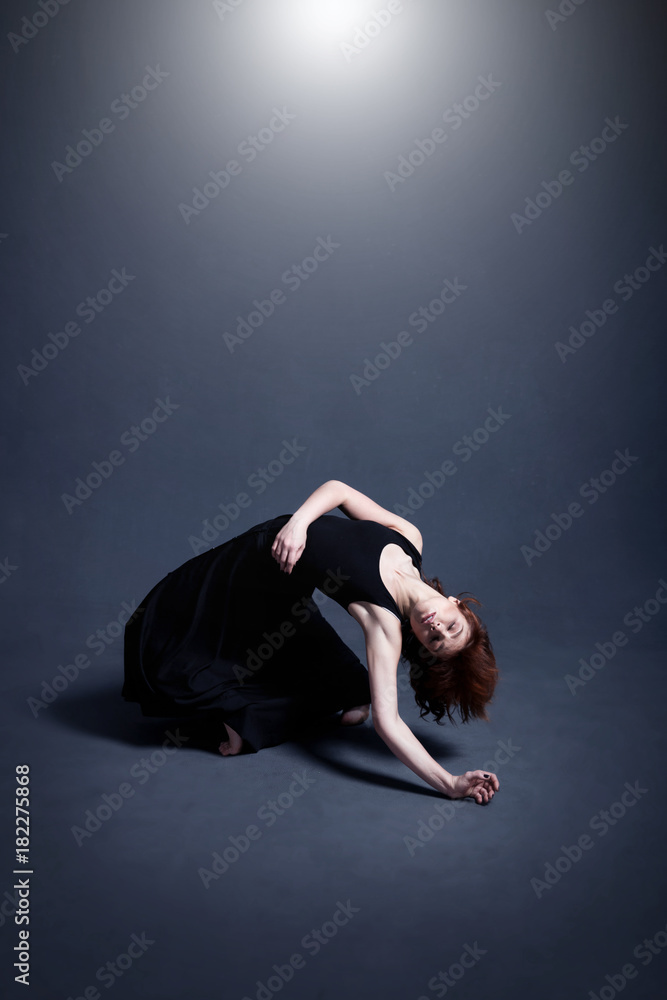 Dancer in a black dress is dancing in the dark studio Dancer in a black dress is dancing in the dark studio
