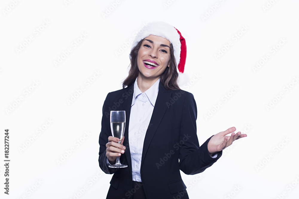 New Year in the office. Beautiful young smiling business woman in santa hat with a glass of champagne on a white background. New Year and Christmas at work. New Year in the office. Beautiful young smiling business woman in santa hat with a glass of champagne on a white background. New Year and Christmas at work.