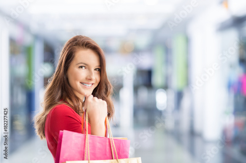 Beautiful happy girl with credit card and shopping bags in shopping mall. Shopping Center in the background.