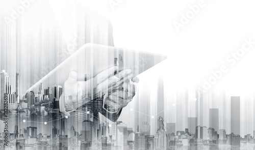 Double exposure Businessman working on digital tablet with modern buildings. Business growth and investment