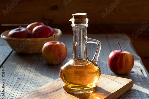 A bottle of apple cider vinegar with apples in the background
