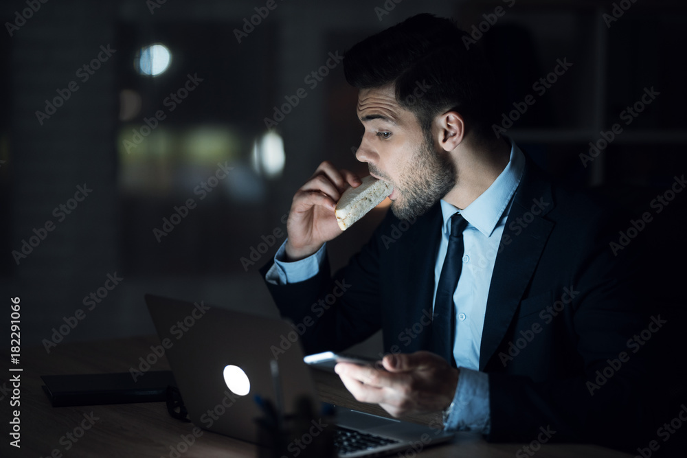 A man is sitting at a laptop in a dark office. The man in the suit works until late. A man is sitting at a laptop in a dark office. The man in the suit works until late.