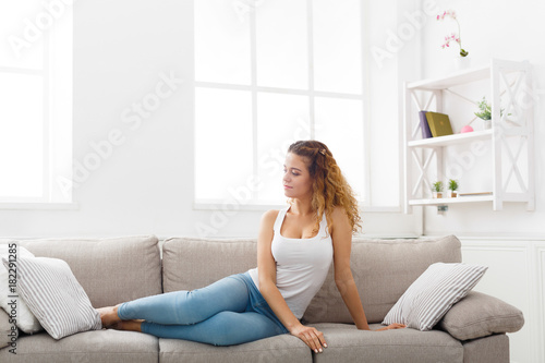 Young redhead woman thinking on beige couch