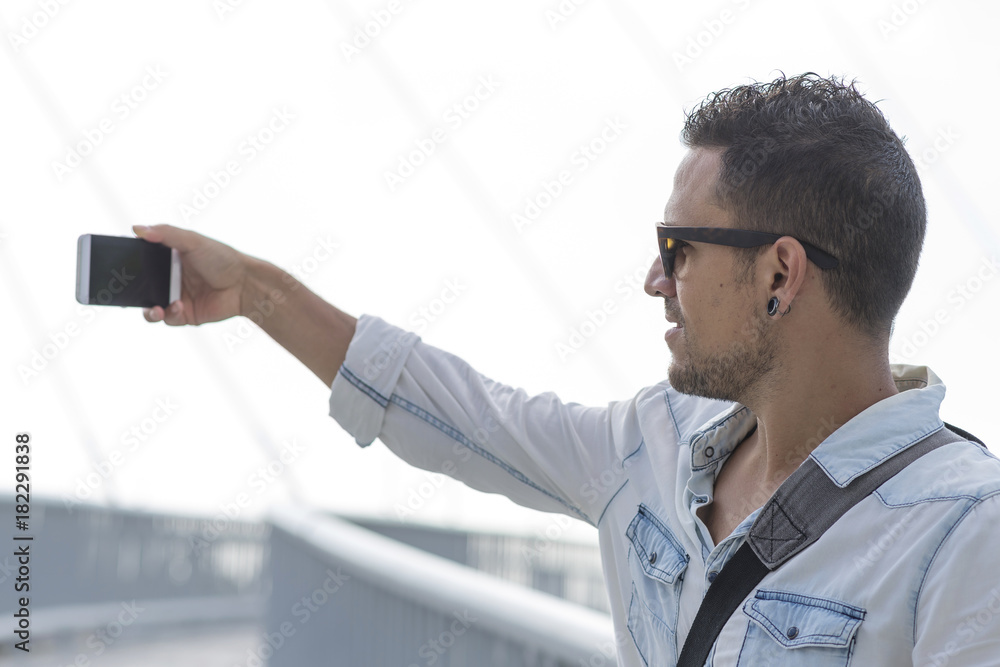 Closeup outdoors shot of young man taking a selfie with smart p Closeup outdoors shot of young man taking a selfie with smart p