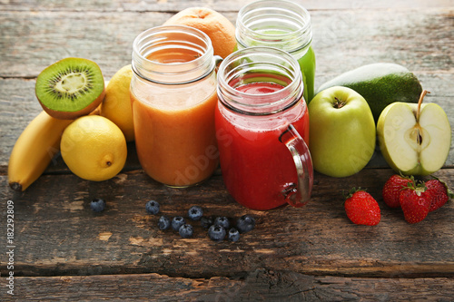 Sweet smoothie in glass jars with fruits on grey wooden table