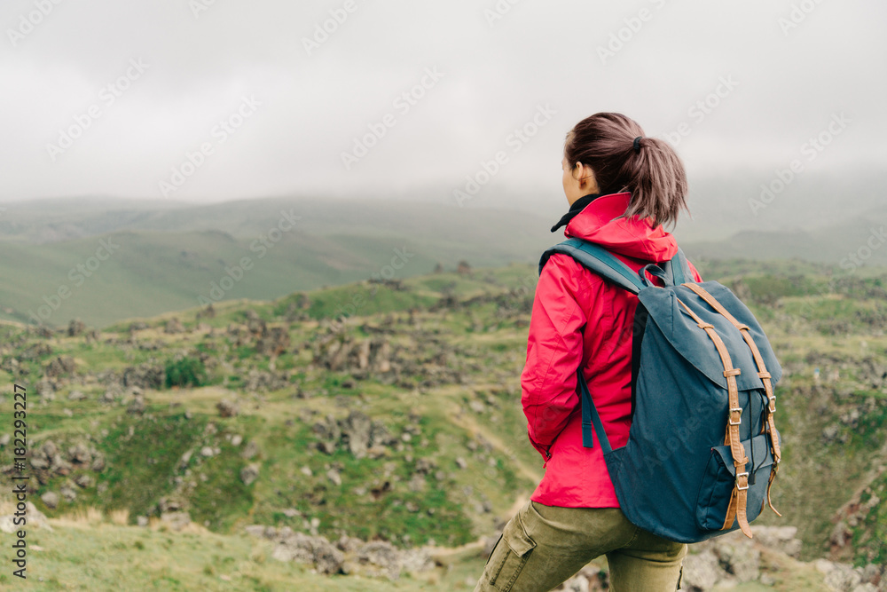 Explorer girl with backpack walking in the mountains.