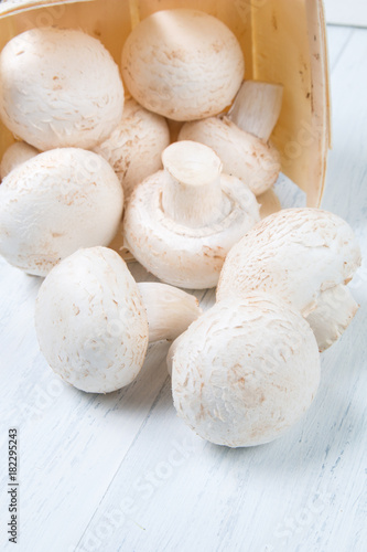 Fresh raw champignon mushrooms on white wooden background