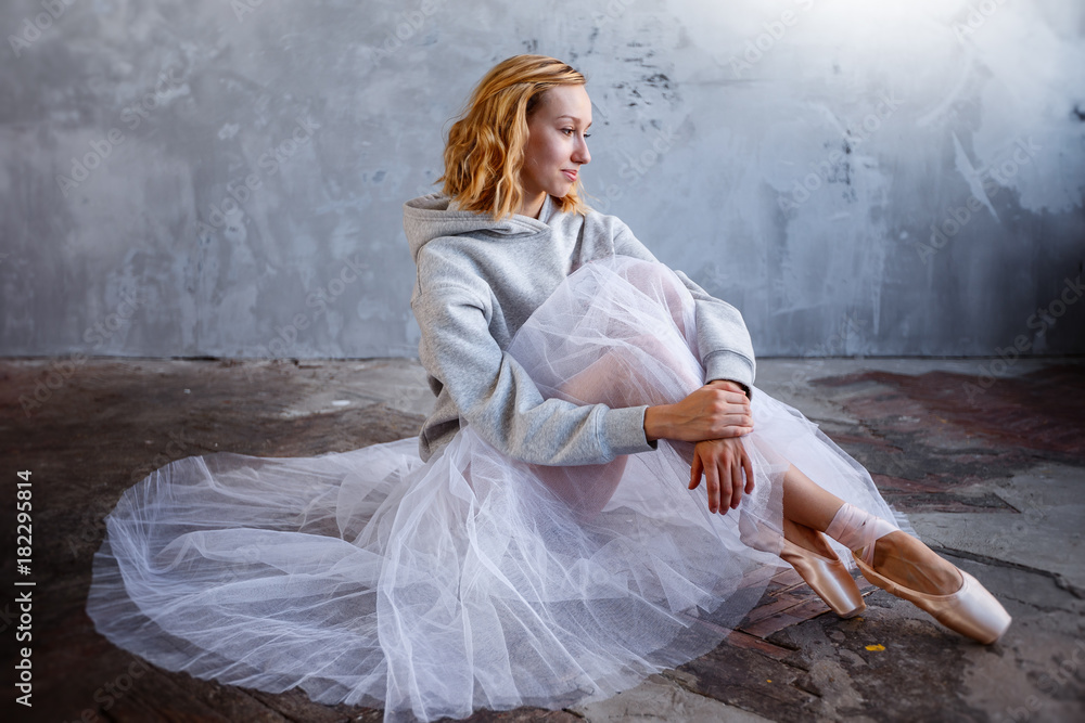 Fototapeta premium Young and slim ballet dancer is posing in a stylish studio with big windows