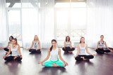 Group of young woman sitting and meditating in lotus pose, yoga concept