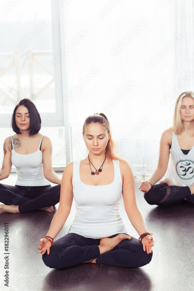 Yoga group concept. Young couple meditating together, sitting back to back on windows background, copy space Yoga group concept. Young couple meditating together, sitting back to back on windows background, copy space
