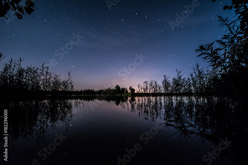 Stars over the lake at summer night on dark sky. Starfall. Milky way.