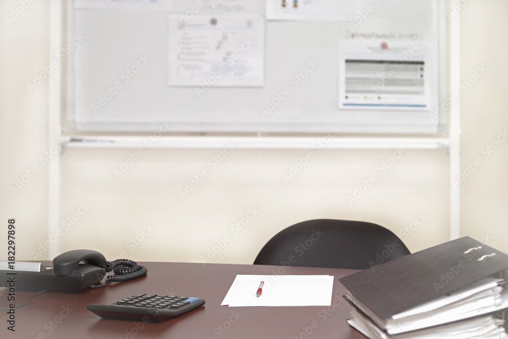 office desk with phone, calculator, sheet of paper, red pen and a magnetic board in the background, toned office desk with phone, calculator, sheet of paper, red pen and a magnetic board in the background, toned
