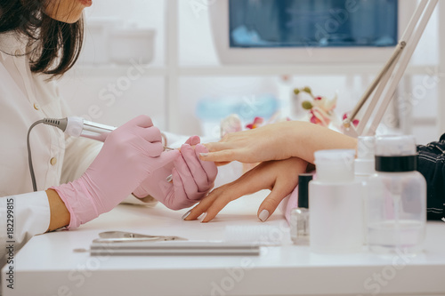 Manicurist with a milling cutter for manicure photo