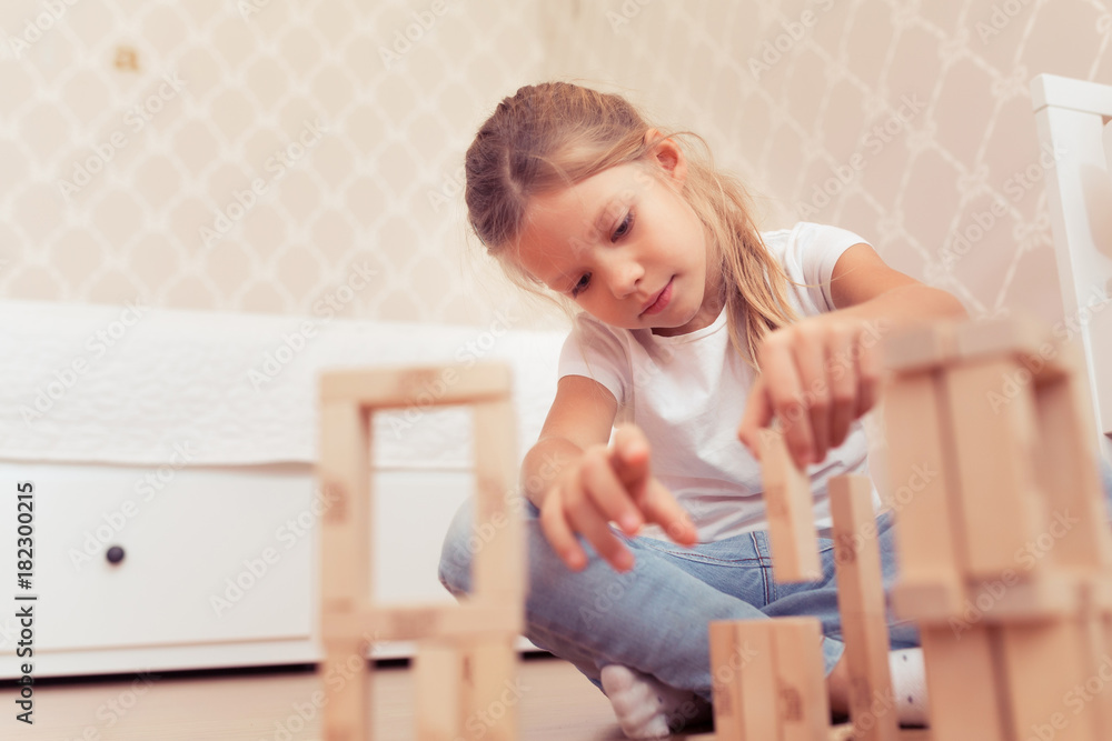 Child little girl playing with wooden blocks the unstable tower Child little girl playing with wooden blocks the unstable tower