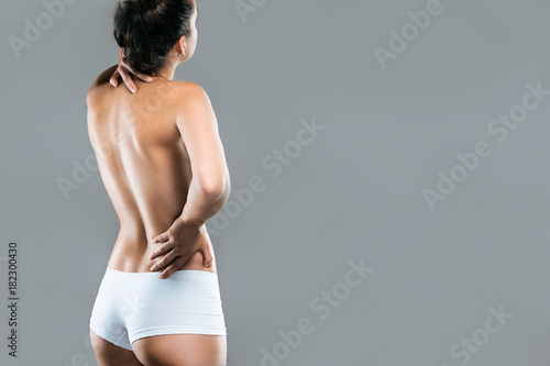 Foto Young woman with pain in neck and back over gray background.