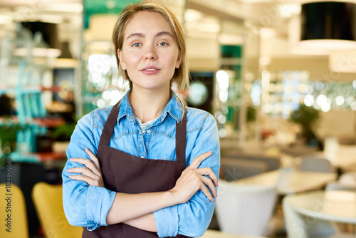 Fotografie Waist up portrait of young waitress wearing apron posing confidently with arms c