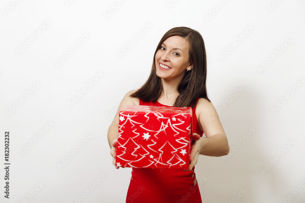 Beautiful caucasian young happy woman with charming smile dressed in red dress and Christmas hat holding gift box on white background. Santa girl with present isolated. New Year holiday 2018 concept Beautiful caucasian young happy woman with charming smile dressed in red dress and Christmas hat holding gift box on white background. Santa girl with present isolated. New Year holiday 2018 concept