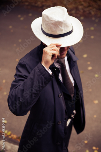 Confident middle-aged wealthy man dressed in retro style suit with white hat