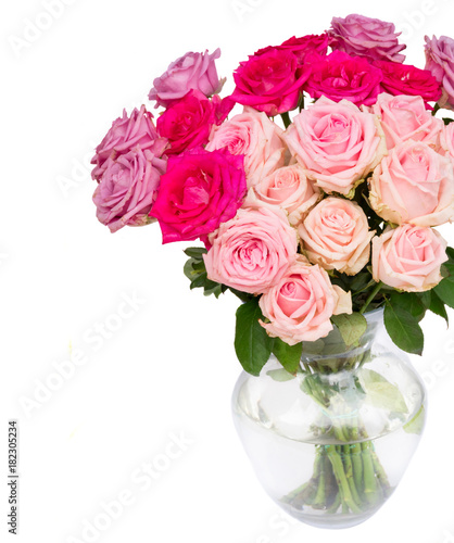 Bunch pink and violet blooming fresh rose flowers in glass vase close up isolated on white background
