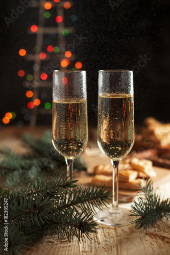 glasses with champagne, biscuits, a Christmas tree and New Year's lights on a New Year's festive table