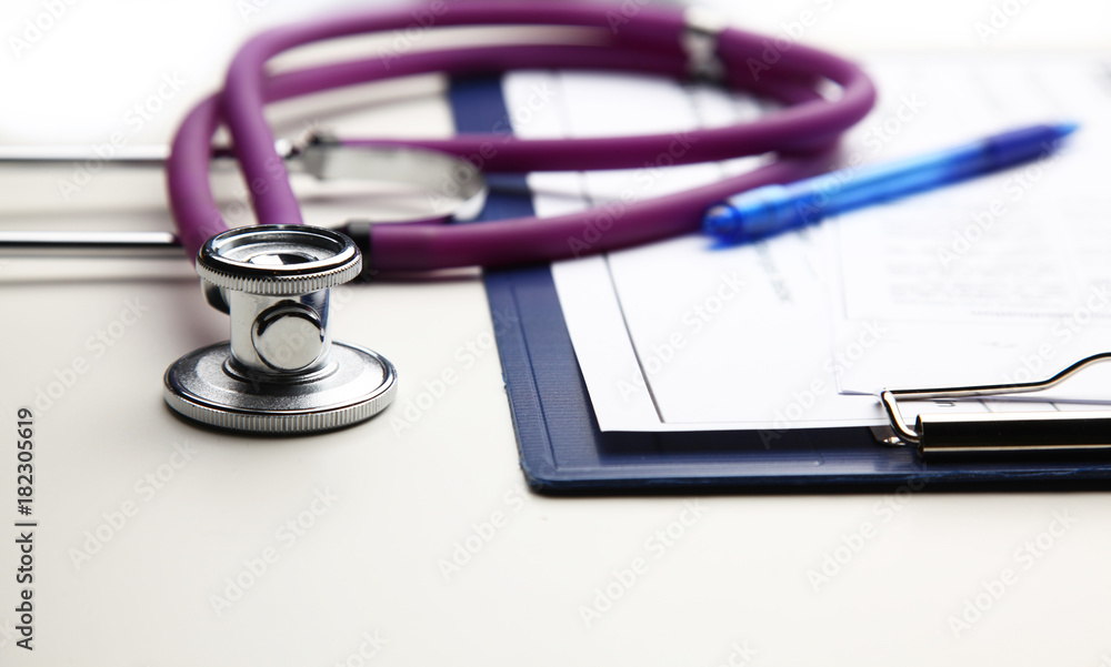 Closeup of medical stethoscope on a rx prescription, red heart isolated on white background Closeup of medical stethoscope on a rx prescription, red heart isolated on white background