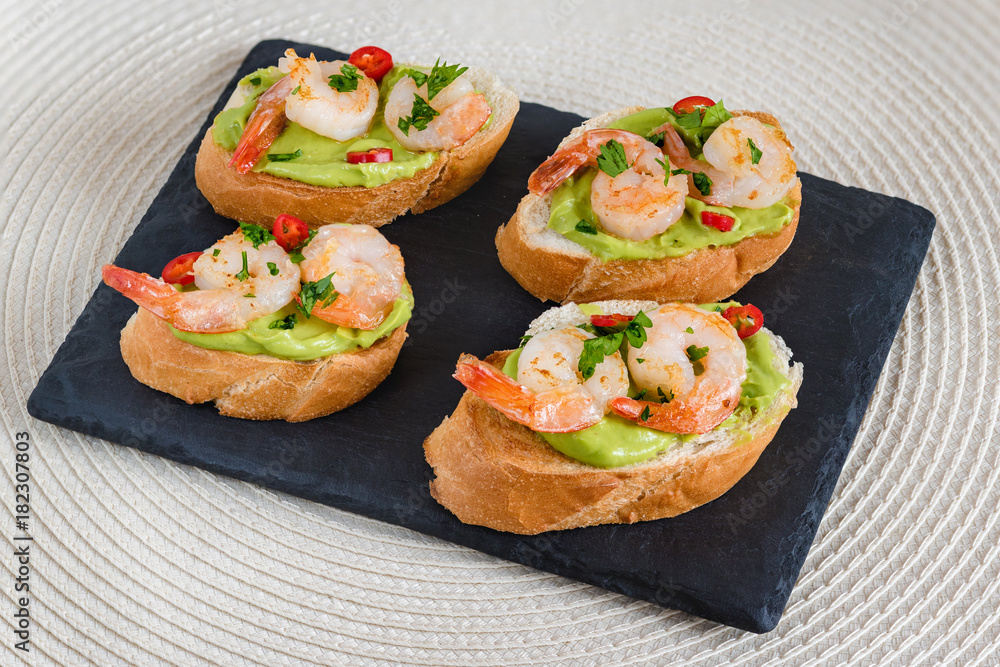 Bruschetta italian snack sandwiches with avocado cream and prawns decorated by parsley and chilli peppers. Bruschetta italian snack sandwiches with avocado cream and prawns decorated by parsley and chilli peppers.