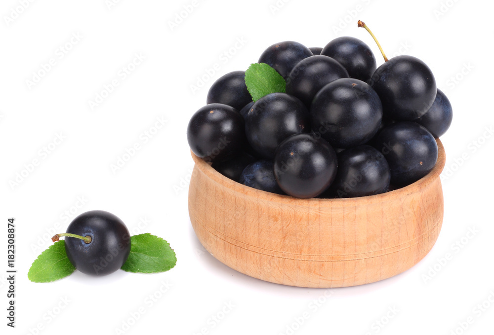 blackthorn berries in wooden bowl with green leaf isolated on white background blackthorn berries in wooden bowl with green leaf isolated on white background