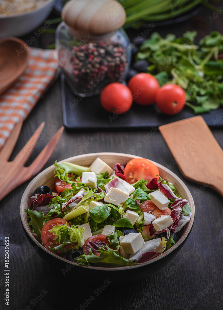 Greek salad and vegetables on the black wood table Greek salad and vegetables on the black wood table