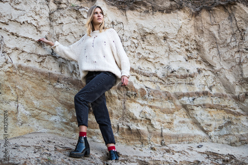 Portrait of a beautiful woman in a white sweater in a sand wall