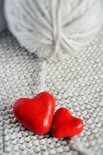 red heart and a ball of threads on a knitted background close-up