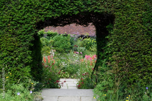 Hedge and a portal, insdie a garden with flowers