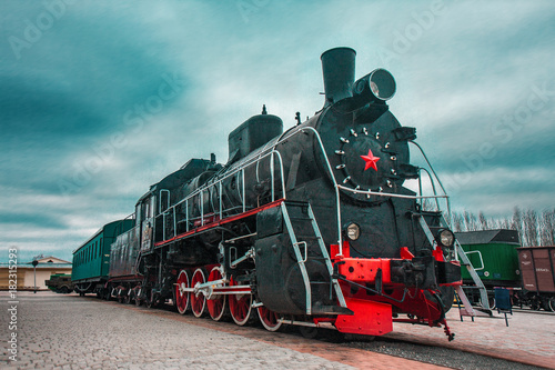 An old black Soviet steam locomotive with a red star on the hull