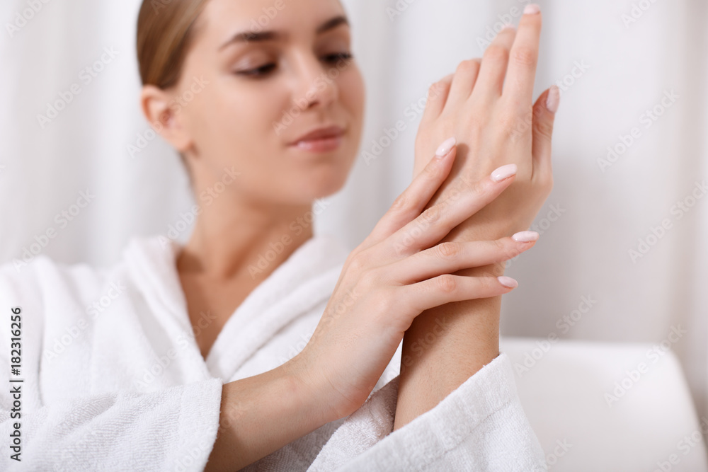 Close up of calm young woman touching her skin at spa procedure with satisfaction. Focus on her hands Close up of calm young woman touching her skin at spa procedure with satisfaction. Focus on her hands