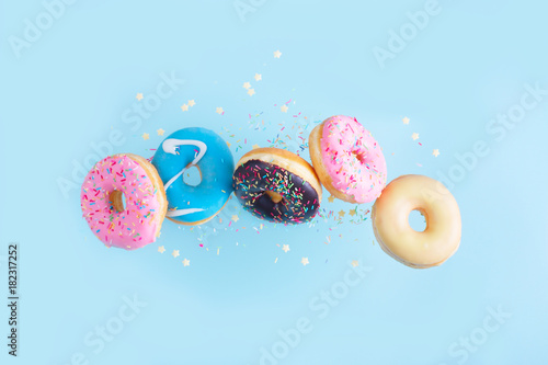 Billede på lærred flying doughnuts - mix of multicolored sweet donuts with sprinkles on blue backg