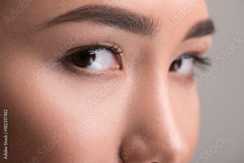 Dreamy look. Close-up of calm young asian female beautiful eyes are looking at camera thoughtfully. Isolated background