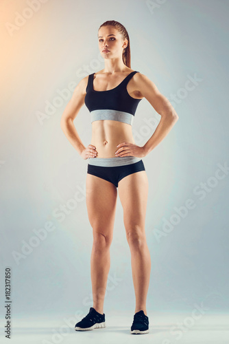 Active lifestyle. Low angle view on a confident young woman posing with her hands on the hips while standing on feet shoulder width apart.