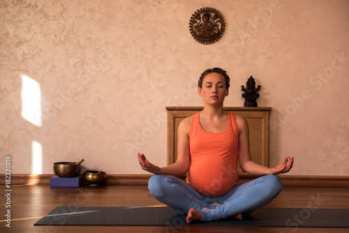 Relaxed impregnate lady wearing comfortable clothes is locating on floor and closing eyes. Portrait. Copy space on left side