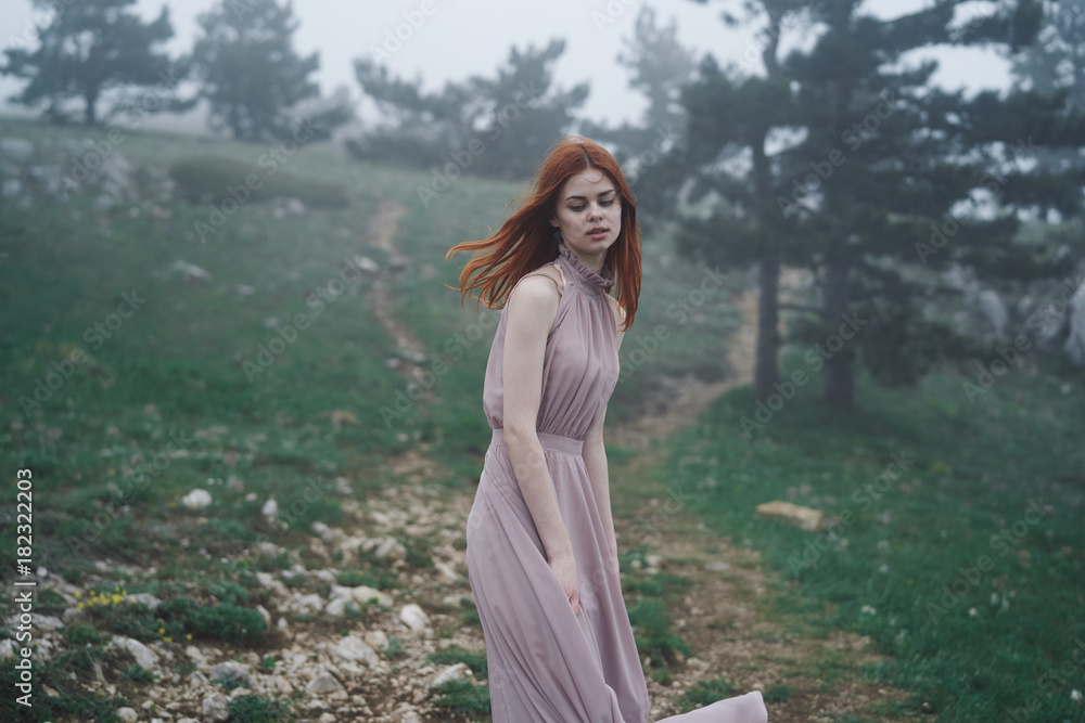 Young beautiful woman in a long pink dress running through the mountains Young beautiful woman in a long pink dress running through the mountains