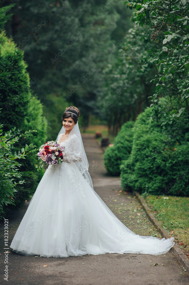 Pretty bride sits on a fountain in the garden Pretty bride sits on a fountain in the garden